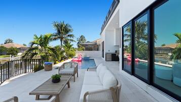A modern outdoor living area with a pool, lounge furniture, and a view of the surrounding landscape.
