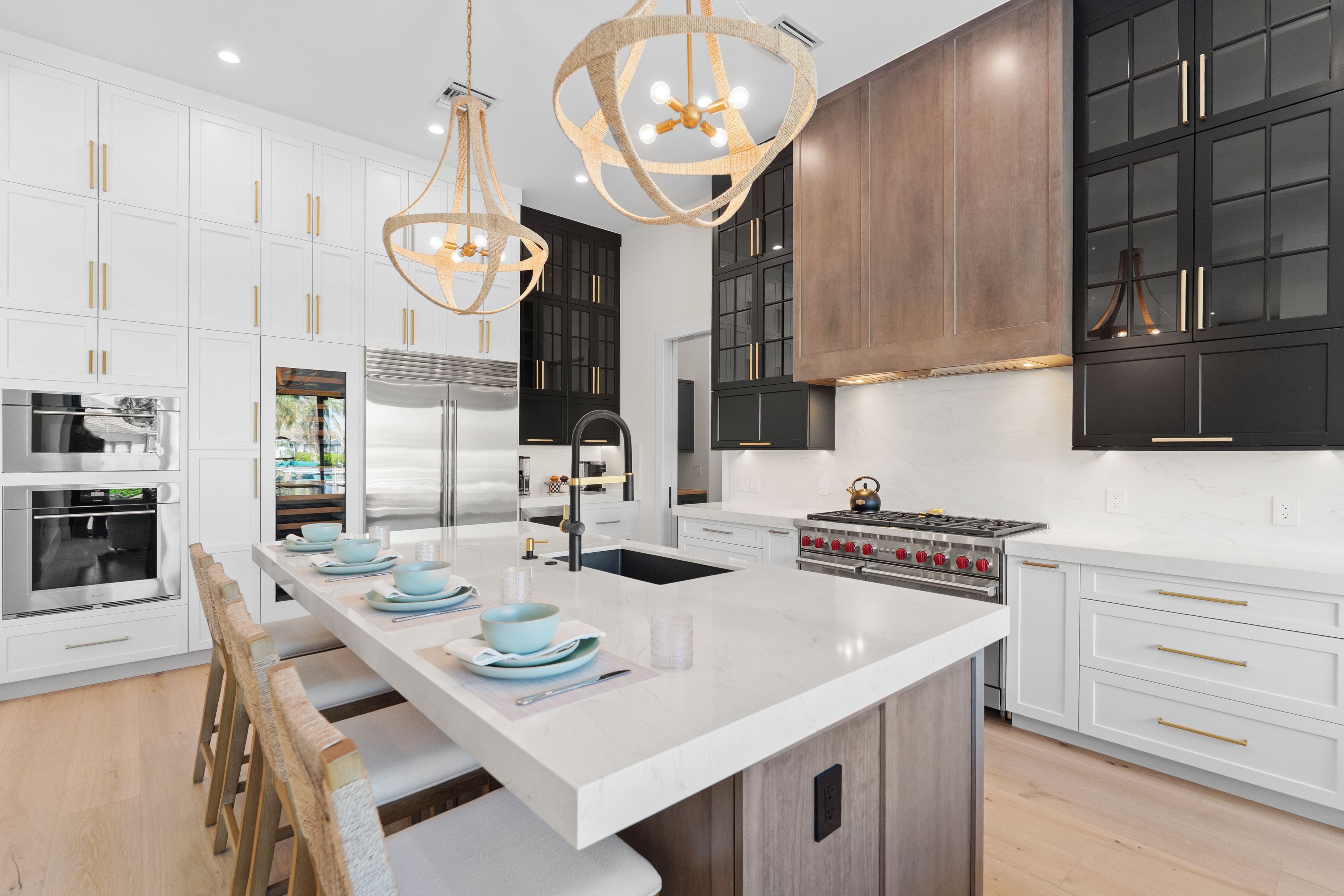 A modern kitchen with white cabinetry, stainless steel appliances, and a large island with seating.
