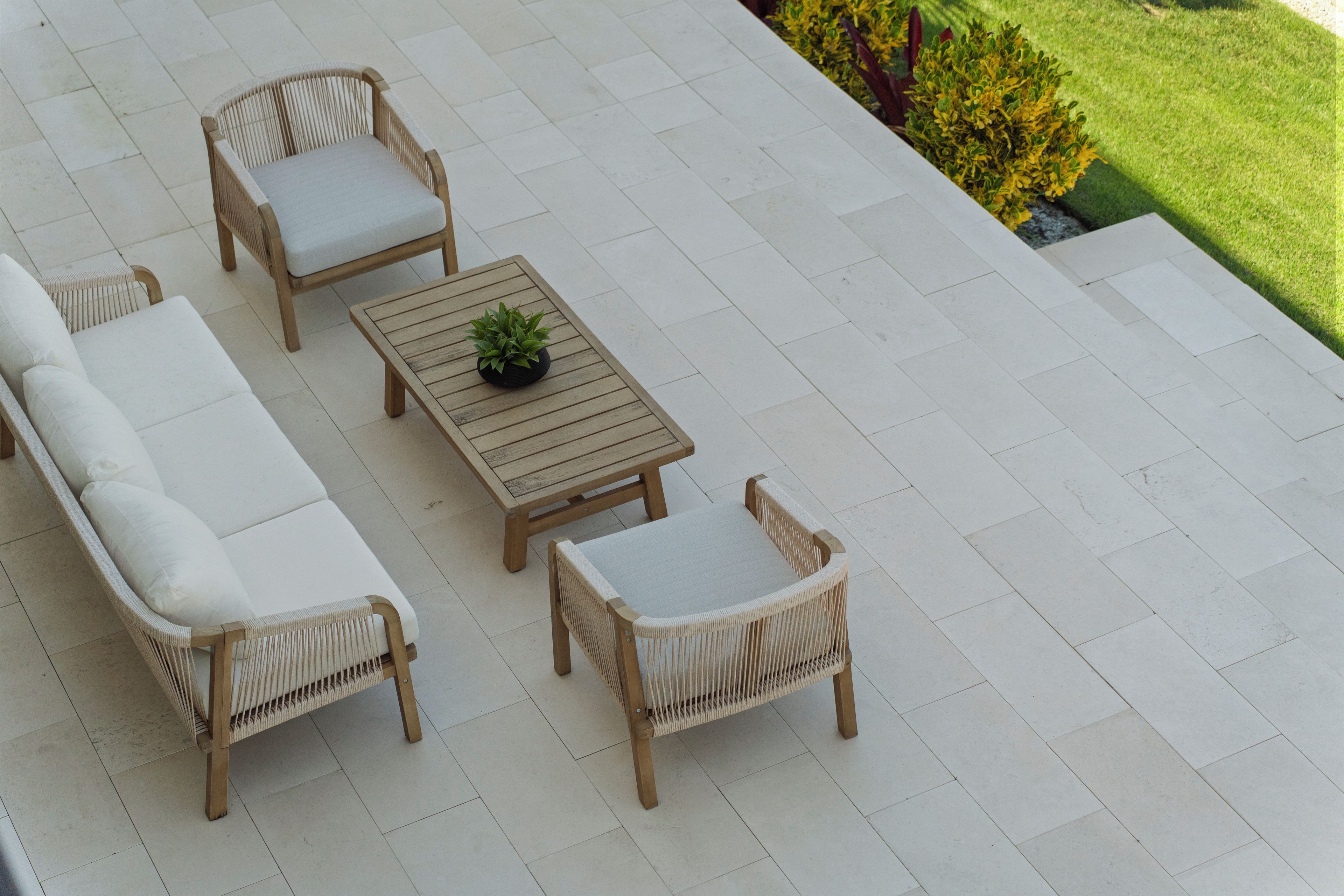 A patio with wicker furniture, including a sofa, two chairs, and a small table with a plant.