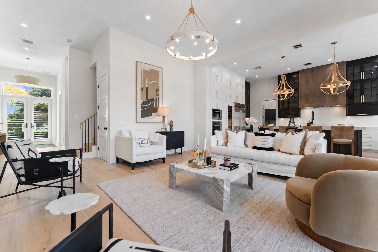 A modern living room with a sofa, armchairs, a coffee table, and a dining area with a kitchen in the background.