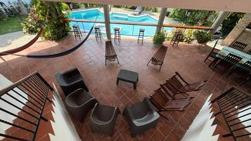 A poolside area with a hammock, lounge chairs, and a table with chairs.