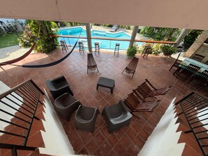 Un área junto a la piscina con una hamaca, sillas de descanso y una mesa con sillas.