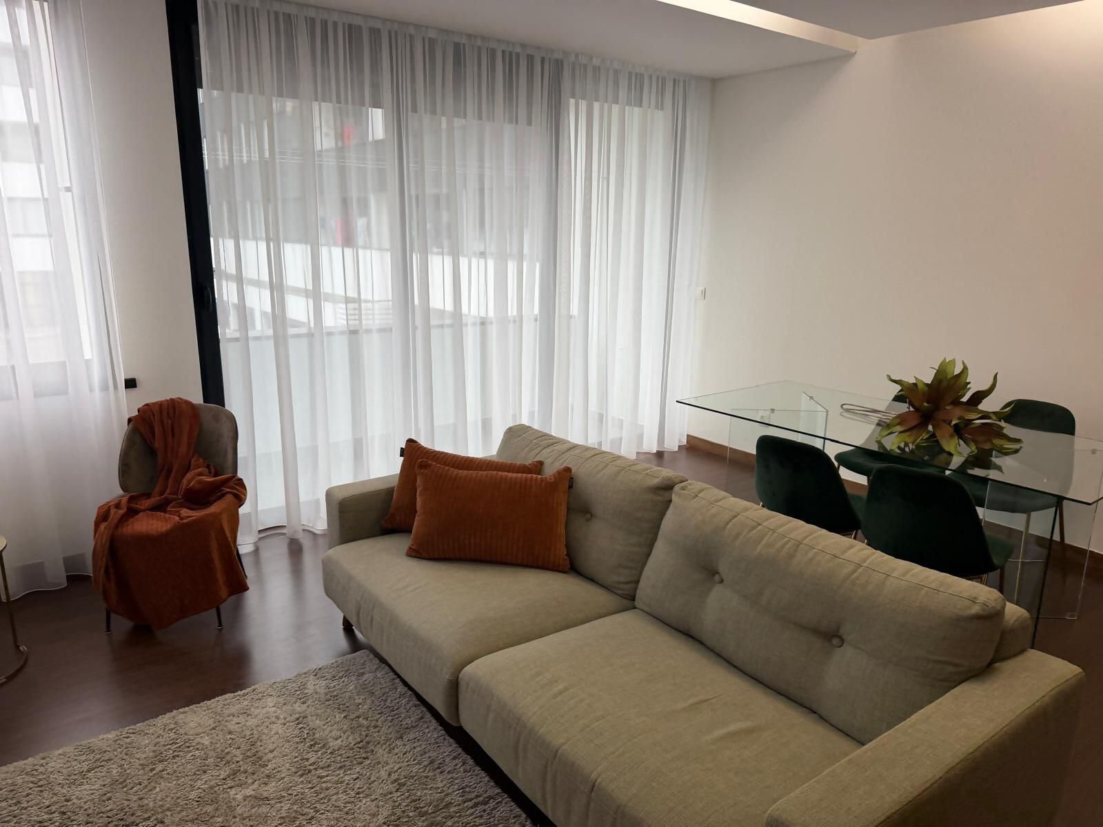 A living room with a sofa, a glass table, and a chair.
