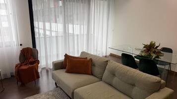 A living room with a sofa, a glass table, and a chair.
