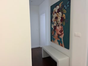 Ein Flur mit einer weißen Bank und einem großen floralen Gemälde an der Wand.
