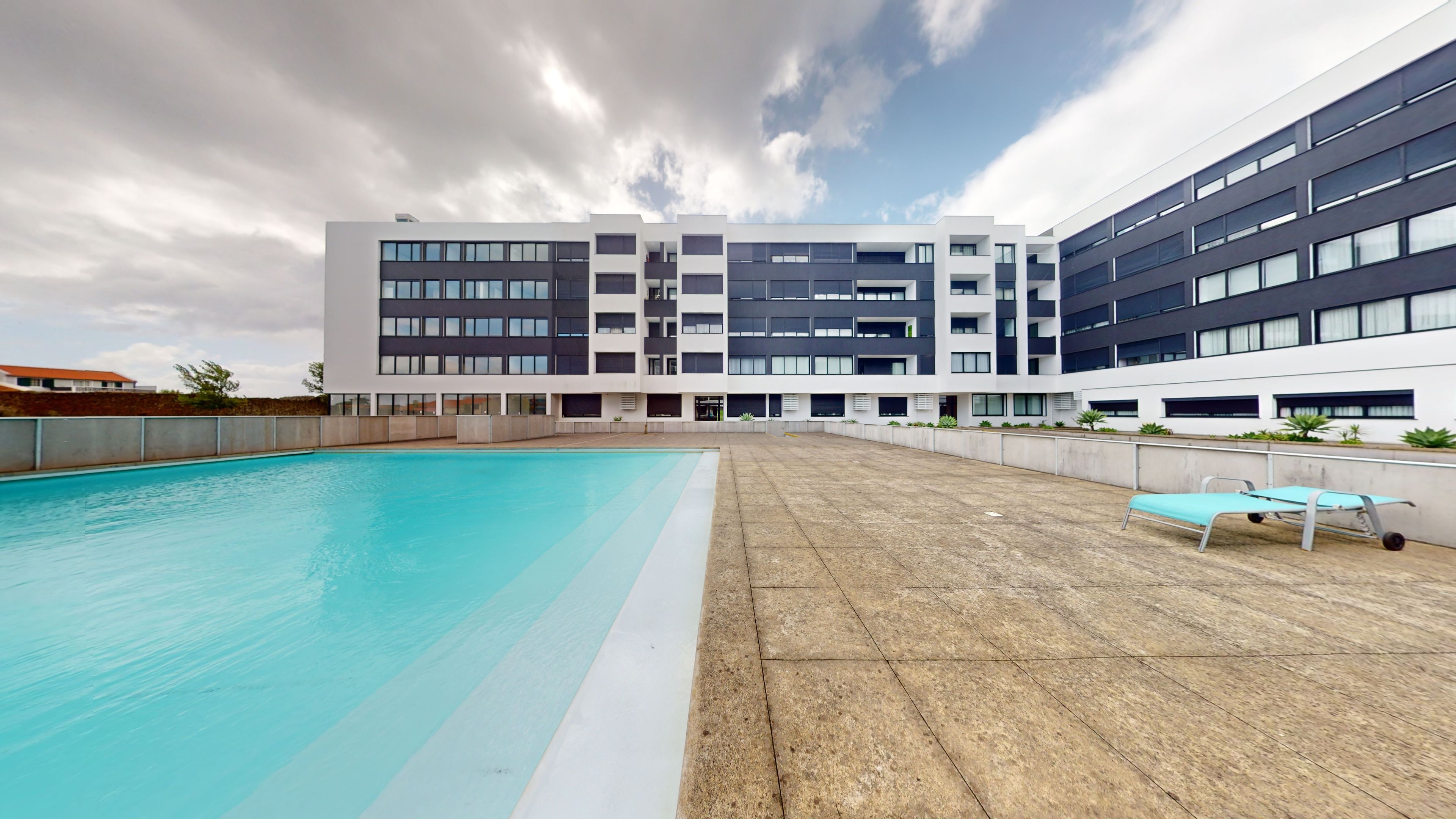 Een modern gebouw met een zwembad en een terras.