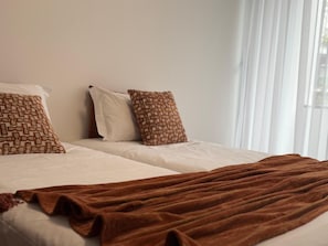 Ein Hotelzimmer mit zwei Betten, einer braunen Decke und gemusterten Kissen.