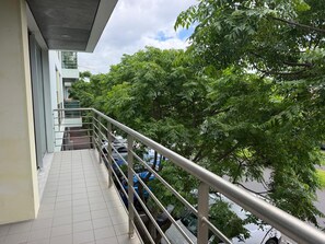 A balcony with a metal railing overlooking parked cars and trees. - AZORES APARTMENTS PAIM 1NASC (Ponta Delgada)