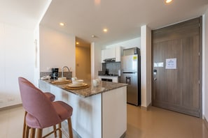 Une cuisine moderne dotée d’un îlot central, de meubles blancs et d’un réfrigérateur en acier inoxydable.