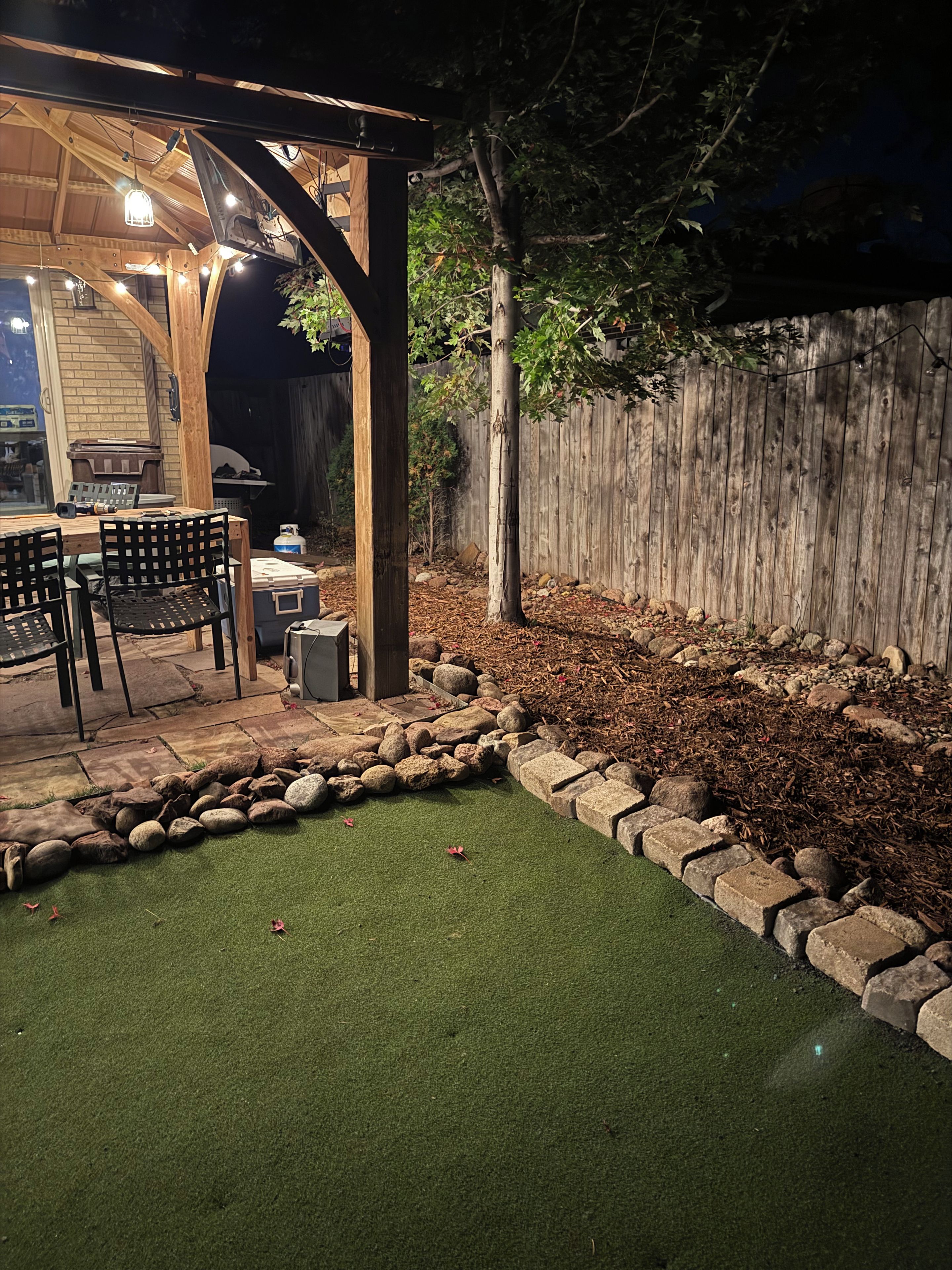 A patio area with a wooden pergola, outdoor seating, and a barbecue grill.