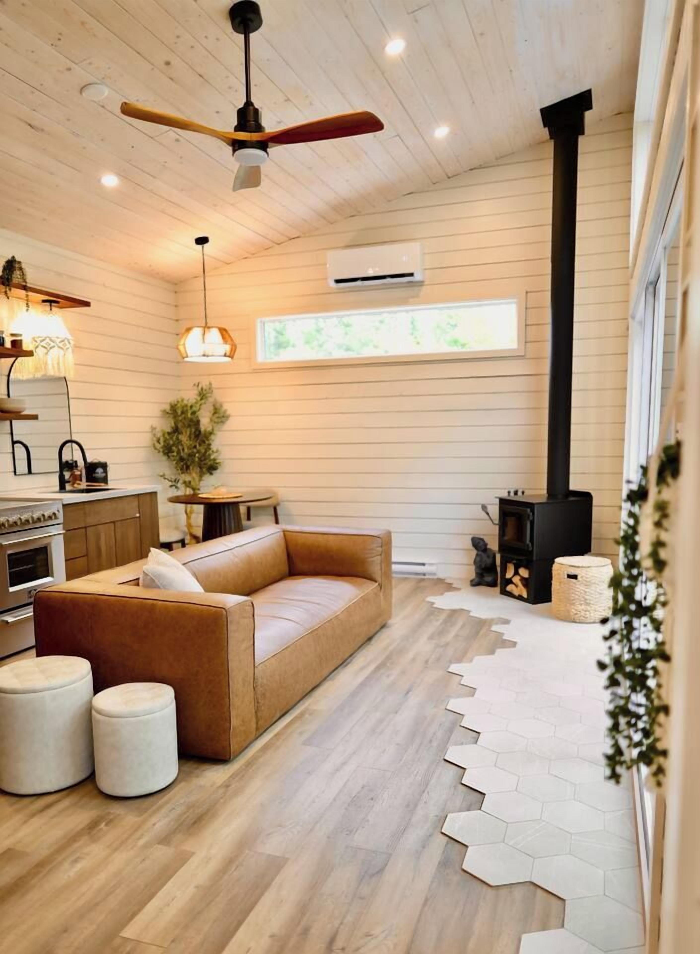 Ein gemütliches Blockhauss Innenleben mit Holzbalkendecke, einer Couch, einem Kamin und einer Küchenzeile.