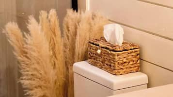 A bathroom with a toilet, a tissue box on the edge, and two macramé wall hangings.