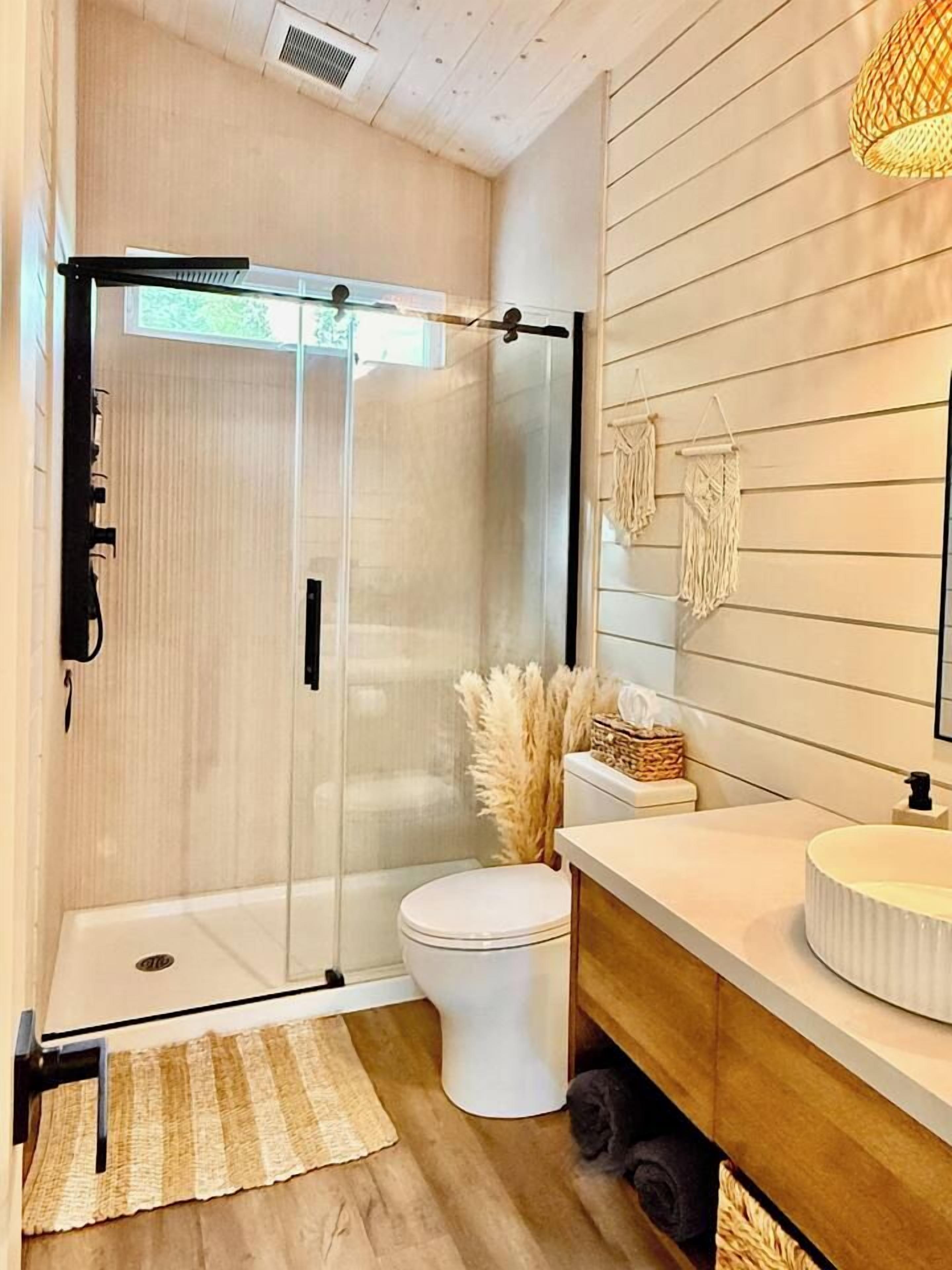 A modern bathroom with a glass shower enclosure, a toilet, a vanity with a sink, and a mirror.