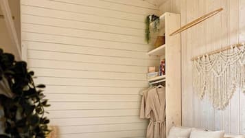 A bedroom with a wooden bed frame, a macrame wall hanging, and a plant.