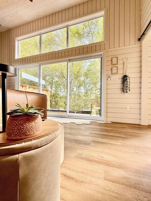 A spacious room with a large window, a potted plant, and a wooden floor.