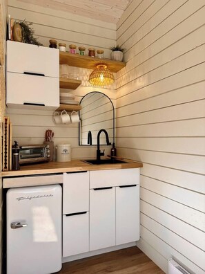 A compact kitchen with a sink, a toaster, and a small refrigerator. - Haven Nature Retreat•Shine & Rise Wellness (Sainte-Marie-de-Kent)