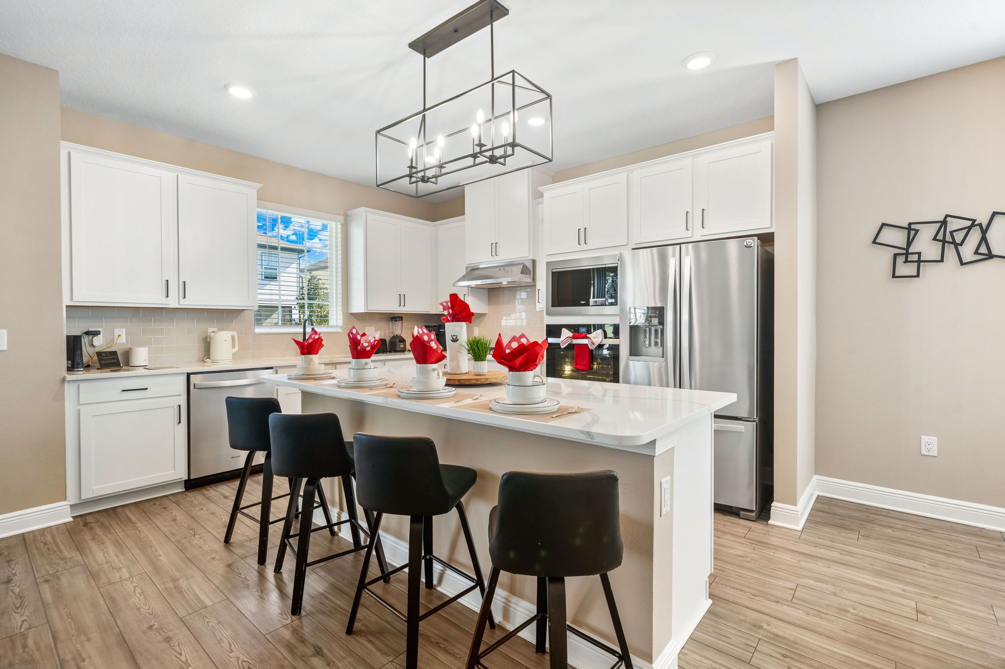 A modern kitchen with white cabinetry, a stainless steel refrigerator, and a central island with bar stools.