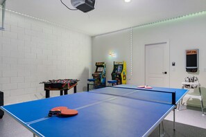 A room with a ping pong table, foosball table, and arcade games. - BRAND NEW | Family Reunion Game Room & Resort Pool 7837 (Kissimmee)