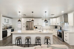 A modern kitchen with white cabinetry, stainless steel appliances, and a central island with bar stools. - PHX | Heated Pool | 10 Min Airport | 18 Scottsdale (Phoenix)