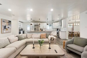 A modern living room with a sectional sofa, a coffee table, and a dining area in the background. - PHX | Heated Pool | 10 Min Airport | 18 Scottsdale (Phoenix)