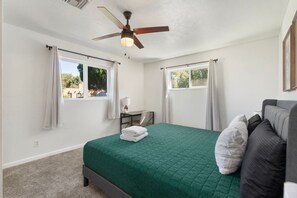A bedroom with a bed, a desk, a chair, a ceiling fan, and two windows with curtains. - PHX | Heated Pool | 10 Min Airport | 18 Scottsdale (Phoenix)