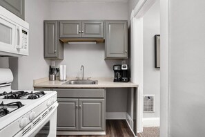 A compact kitchen with a gas stove, a sink, and a coffee maker. - The Dingo - Sunny One Bed Apt, Walk to Mass Ave (Indianapolis)