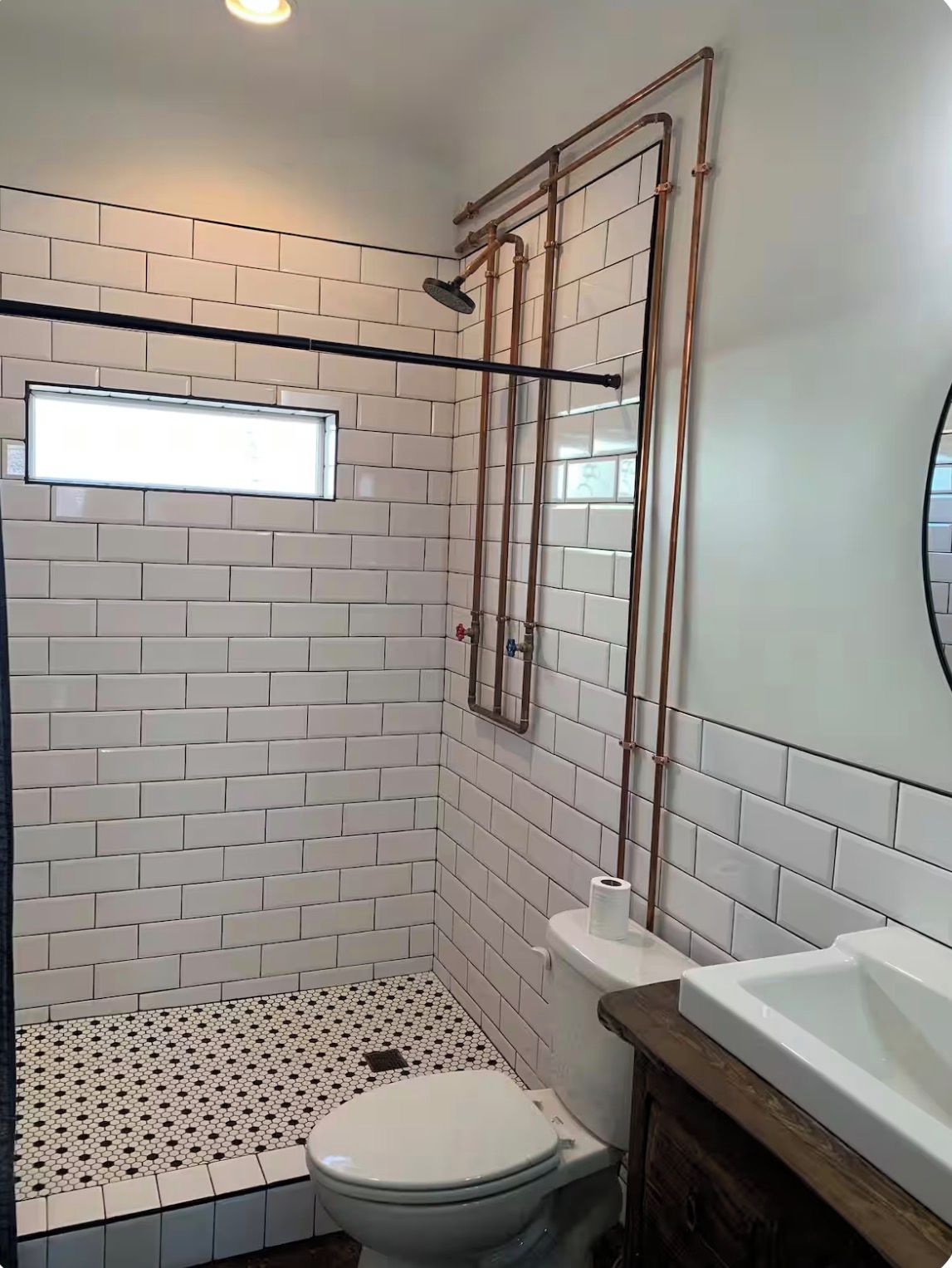 Ein Badezimmer mit Duschkabine, Toilette und Waschbecken, alles in weißen Fliesen.
