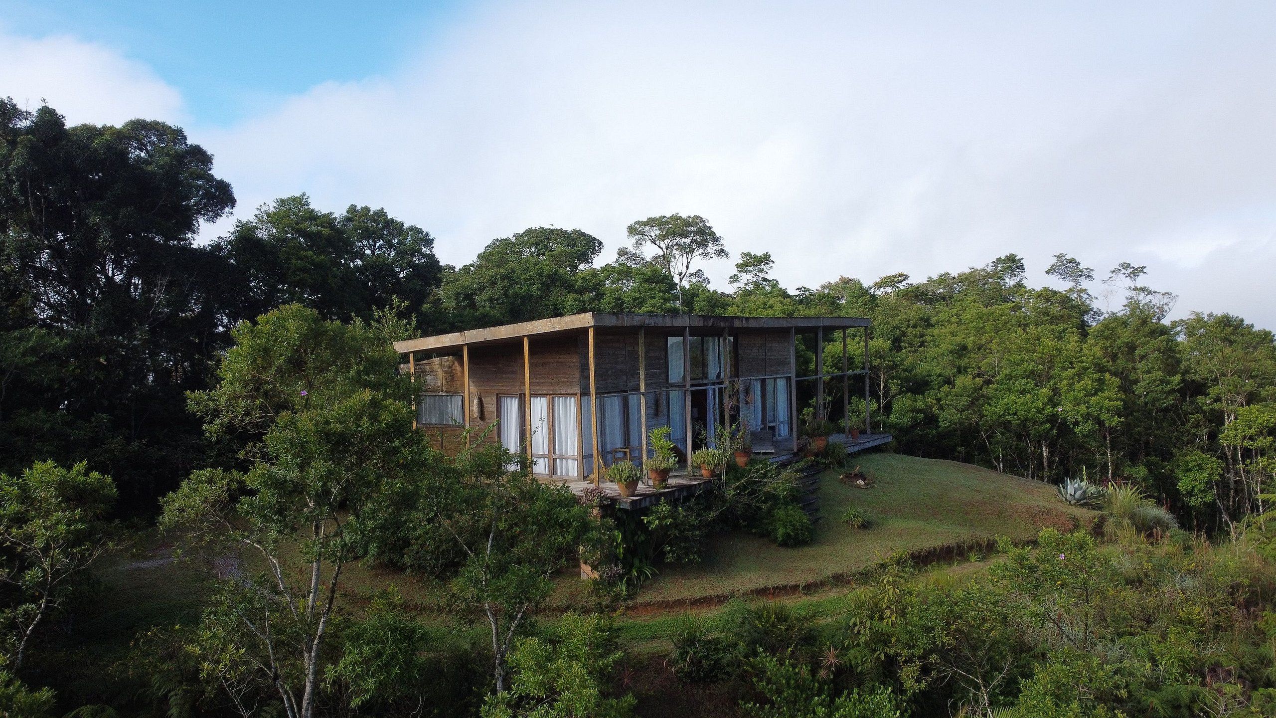 Uma casa moderna com telhado plano, janelas amplas e varanda coberta.