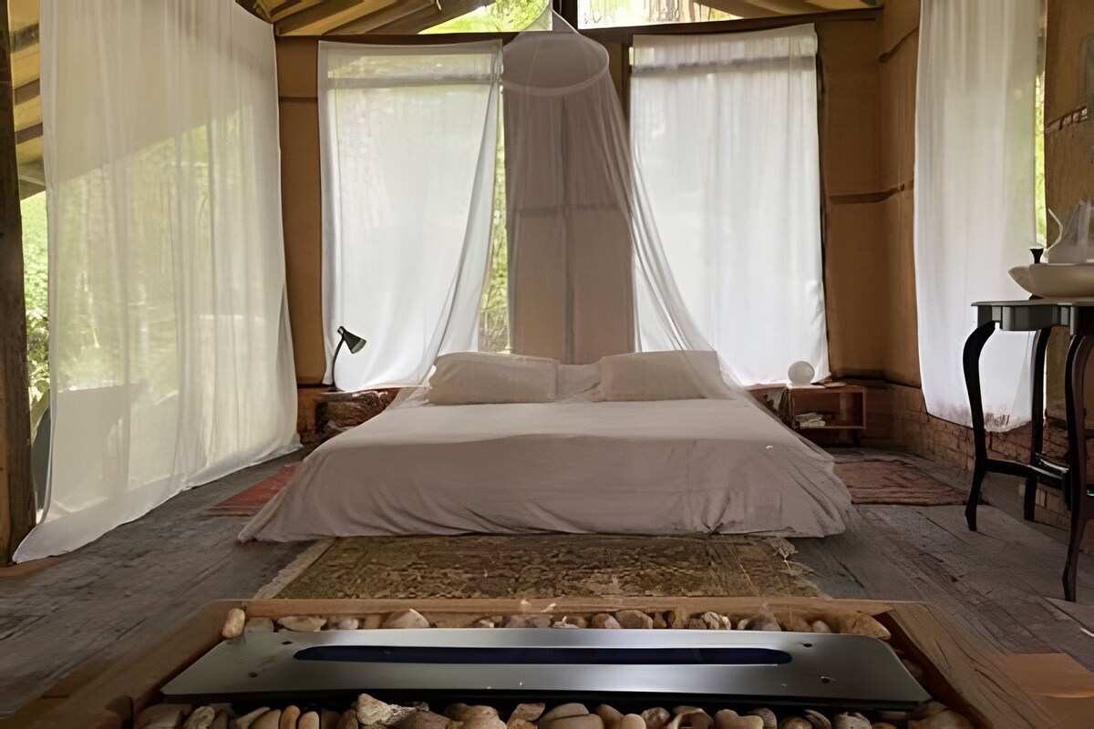Un dormitorio con cama, mesitas de noche y un dosel.