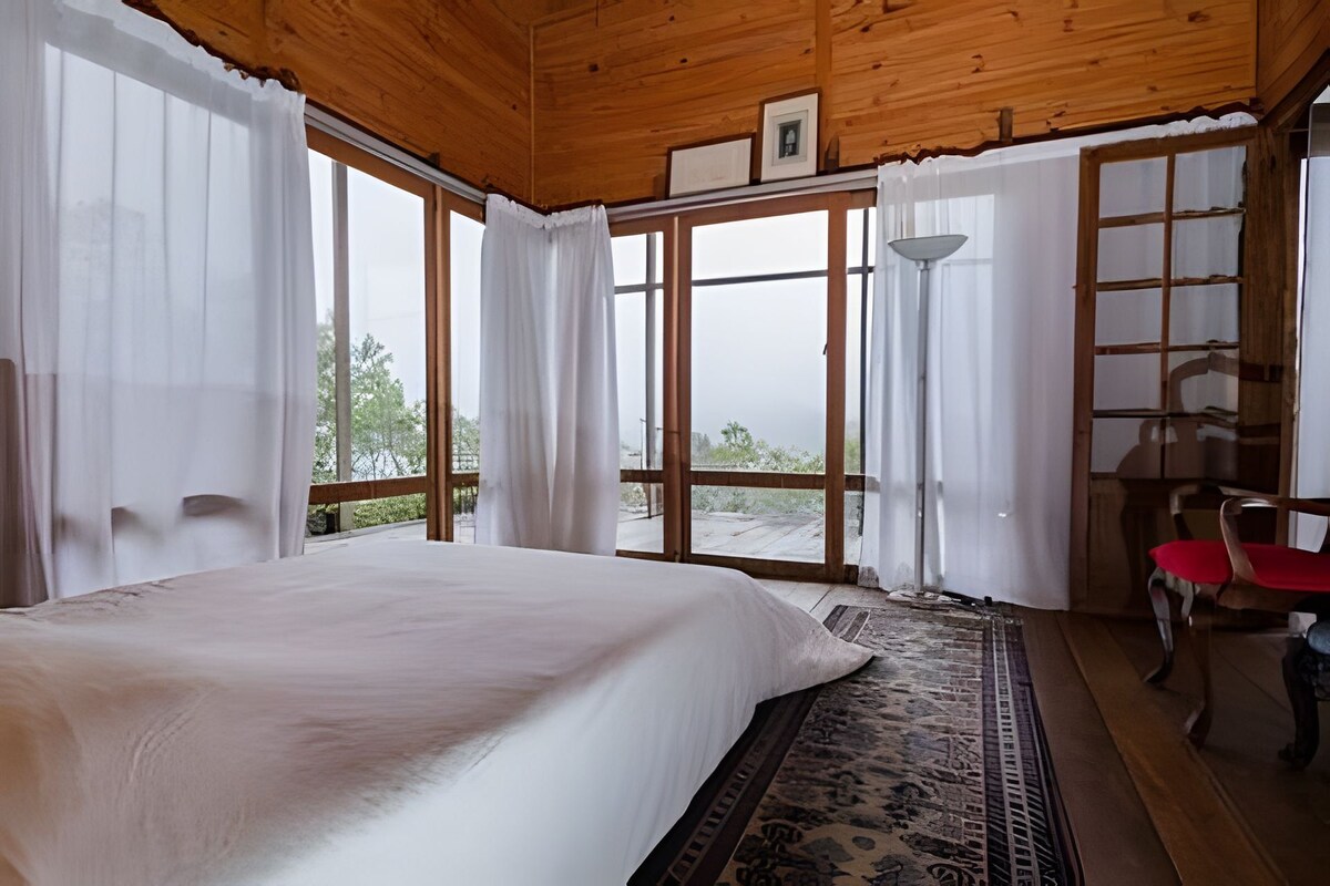 Un dormitorio con una cama grande, techo de madera y vistas a través de la puerta de cristal.