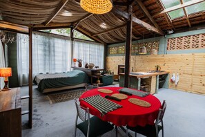 Una habitación rústica con una cama, una mesa de comedor y una zona de cocina.