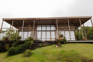A modern building with a flat roof, large windows, and a covered entrance area. - Macondo uma Vila (Tapirai)