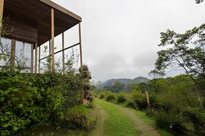 A building with a wooden structure and a path leading to a mountainous landscape. - Macondo uma Vila (Tapirai)