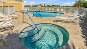A pool area with multiple lounge chairs and a small pool. - Coastal Luxury at Vanderbilt Beach! (Naples)