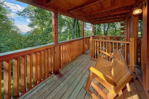 A wooden deck with a bench, surrounded by trees. - 2BR Cabin with Hot Tub, Game Room, Wooded Views + Free Tix (Sevierville)