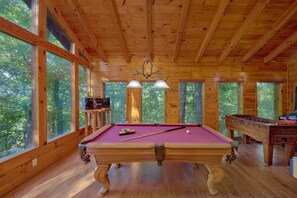 A wooden recreational room with a pool table, a foosball table, and a bar area with a television and speakers. - 2BR Cabin with Hot Tub, Game Room, Wooded Views + Free Tix (Sevierville)