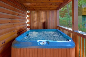 A hot tub on a wooden deck with a view of trees. - 2BR Cabin with Hot Tub, Game Room, Wooded Views + Free Tix (Sevierville)