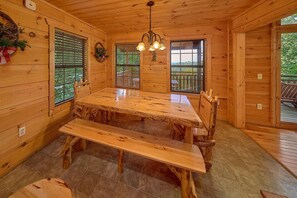 A wooden interior with a dining table, benches, and a chandelier. - Mountain Bearadise | Theater, Hot Tub, Game Room, Sleeps 12, Fireplace + Free Attraction Tickets (Sevierville)