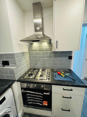 A kitchen with a gas stove, oven, and stainless steel range hood. - 3BR Home with Large Garden in Leicester (Leicester)