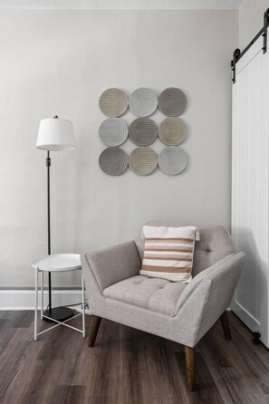 A modern living room with a grey armchair, a round side table, and a floor lamp. - The Koala - Sunny King Studio -Walk to Mass Ave (Indianapolis)