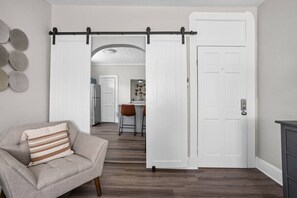 Una habitación con una puerta corrediza de estilo rústico que da a una zona de cocina.