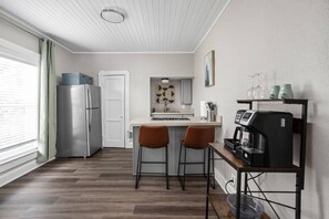 A compact kitchen with a refrigerator, a coffee machine, and two bar stools. - The Koala - Sunny King Studio -Walk to Mass Ave (Indianapolis)