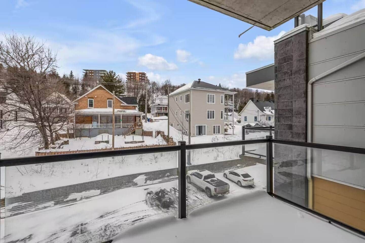 Un balcon donnant sur un quartier résidentiel, avec vue sur les maisons et les voitures garées.