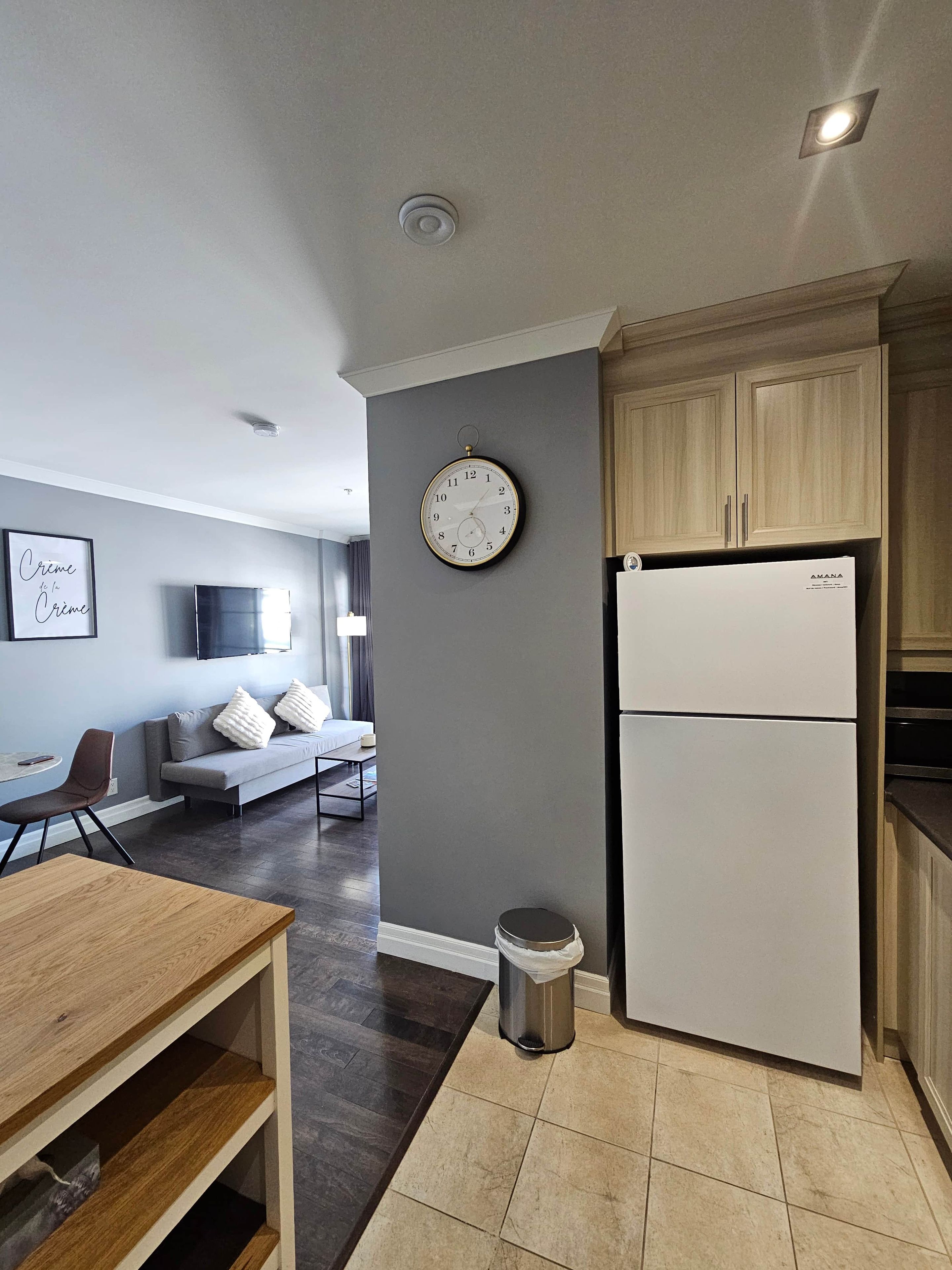 Una cocina moderna con un refrigerador empotrado, un reloj de pared y un cesto de basura.