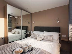 A hotel room with a bed, bedside table, and a large mirror reflecting the room. - Whispering Reeds, Hot Tub and Private Quay, Horning (Horning)