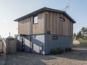 A two-story building with a wooden exterior and a grey lower section. - Whispering Reeds, Hot Tub and Private Quay, Horning (Horning)