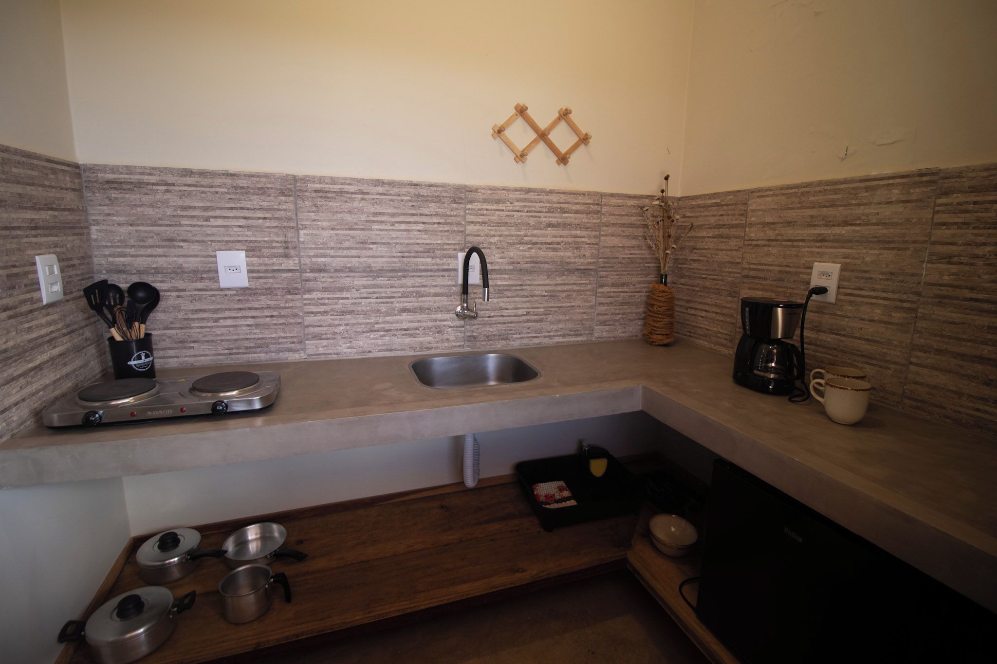 A compact kitchen with a sink, a coffee maker, and a stove.