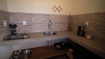 A compact kitchen with a sink, a coffee maker, and a stove.