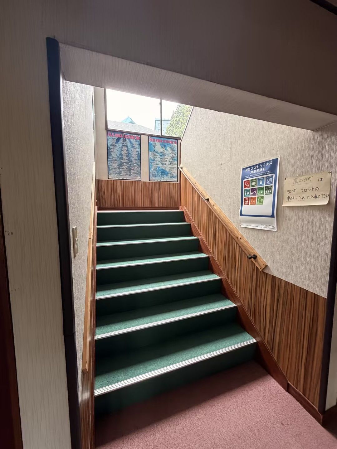 A staircase with wooden handrails and carpeted steps leading to an upper floor.