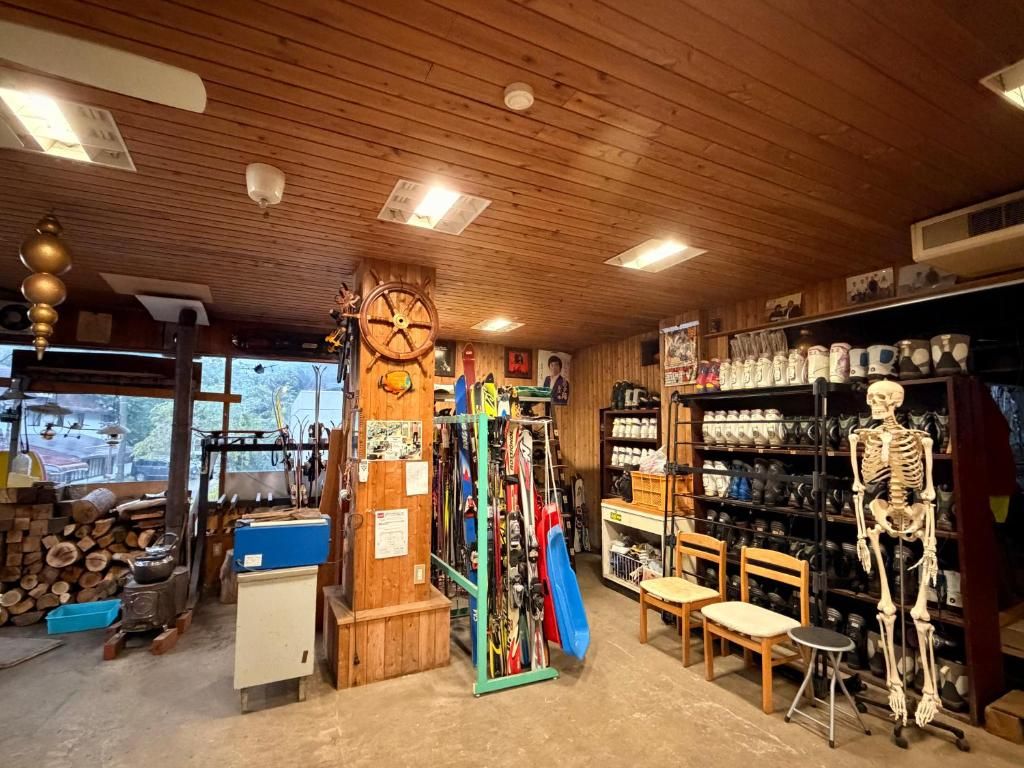 A rustic interior with wooden beams, a skeleton model, and shelves with various items.